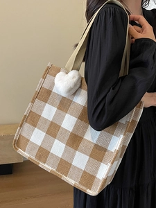 Large plaid tote bag with plush heart charm shown on model in a casual autumn outfit
