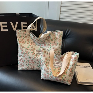 Ensemble de sacs cabas en toile fleurie en deux tailles avec poignées tissées sur canapé