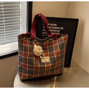 Close-up of vintage plaid canvas tote bag with red handles and cute plush charm detail