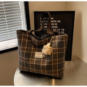 Close-up of vintage plaid canvas tote with thick strap and plush chick pendant