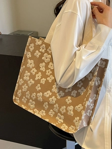Brown jacquard tote bag with white 3D flower patterns and cream woven straps on a model
