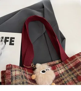 Detail of red plaid tote bag with sturdy wine red handle and plush sunglasses pendant
