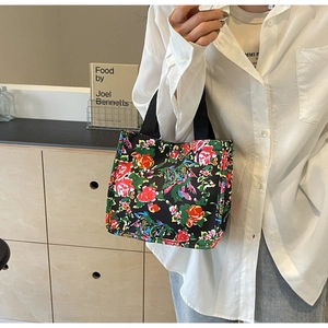 Detail of vintage floral canvas tote bag with red roses and durable black handles