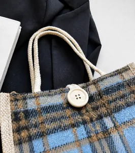 Detail der karierten Woll-Tasche mit robusten Baumwollseilgriffen und Holzknopfverschluss