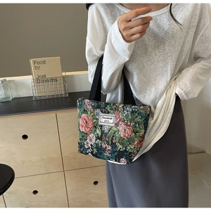 Detail of floral tapestry tote bag with pink rose patterns and black woven handles