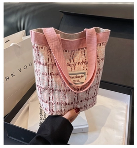Close-up of pink and white tweed bucket bag featuring a woven label with textile handle