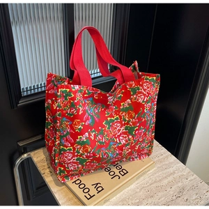 Detail of red floral canvas tote bag with vibrant rose pattern and durable red handles