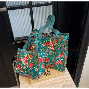 Detailed view of two floral canvas tote bags in different sizes with red rose patterns