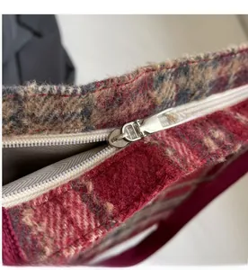 Détail du zip argenté fluide sur un sac cabas en laine à carreaux rouges et bleus