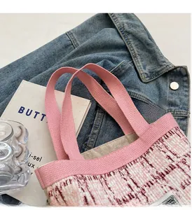 Detail of pink and red tweed woven bucket bag with canvas handles on denim background