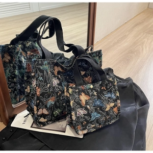 Detailed macro of black jacquard fabric with colorful woven butterfly patterns on a tote bag