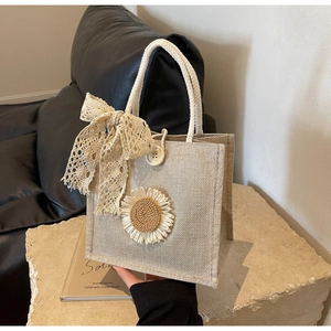 Detailed texture of beige linen tote bag with lace bow and woven sunflower accessory