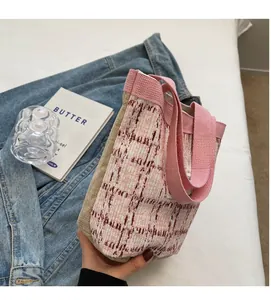 Close-up of a pink and beige woven bucket bag with a soft fabric handle and stylish texture