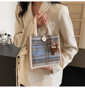 Detail of blue and brown plaid linen tote bag featuring a cute plush monster charm