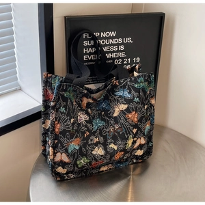 Close-up of jacquard tote bag featuring colorful butterfly patterns on black fabric