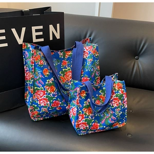 Blue canvas tote bag set with red floral pattern on a black leather sofa