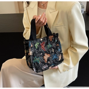 Detail of black tote bag with colorful butterfly embroidery and metal magnetic closure