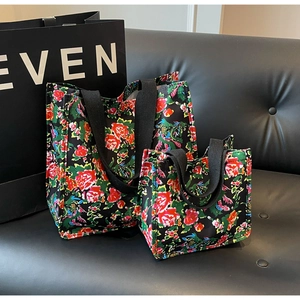 Macro detail of large and small floral tote bags with colorful rose patterns on black canvas