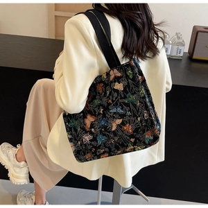 Detail of artistic butterfly embroidery on a black canvas tote bag for women