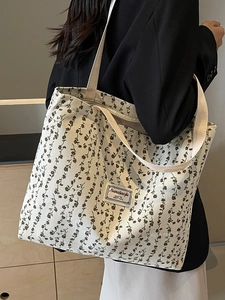Grand sac cabas en velours côtelé fleuri pour le trajet quotidien porté à l'épaule par un mannequin