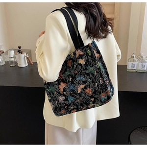 Model wearing large black tote bag with colorful butterfly jacquard and wide strap