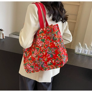 Detail view of a large vintage floral tote bag with vibrant red and green patterns