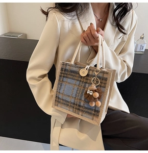 Detail of blue and beige checkered linen tote bag with rope handle and plush charm accessory