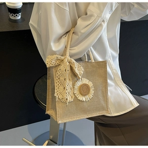 Detail of jute tote bag with a sunflower appliqué and lace bow in a lifestyle setting