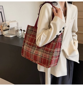 Close-up of vintage red plaid tweed tote bag with woven texture and flat shoulder strap