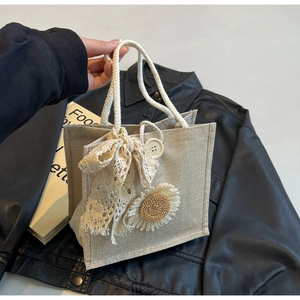 Detail of beige jute handbag with lace bow, sunflower patch and white cotton rope handle