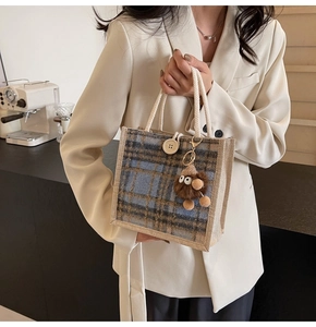 Detail of plaid wool tote bag with thick rope handles and dark brown plush pendant