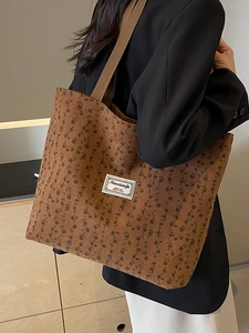 Grand sac fourre-tout en velours côtelé marron à fleurs porté par un mannequin élégant