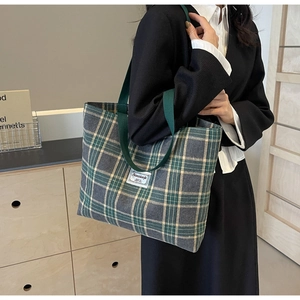 Detail of green plaid canvas tote bag showing textured fabric and brand label