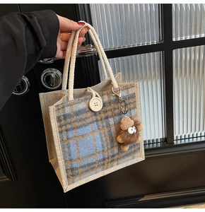 Close-up of linen checkered tote bag with woven cotton rope handle and plush monster charm