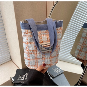 Close-up of a mini tweed bucket bag with blue plaid patterns and a thick woven handle