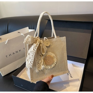 Detail of beige woven lunch bag featuring a yellow lace bow and knitted sunflower decor