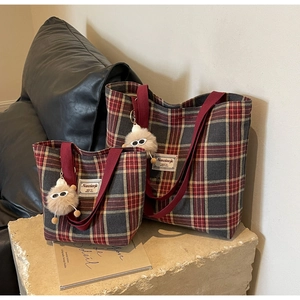 Detailed view of plaid canvas tote bags in red and black with plush ball charms