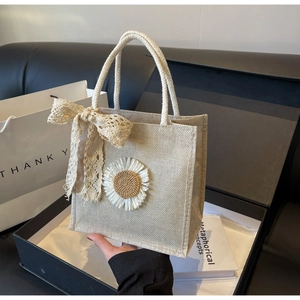Detail of beige canvas lunch bag with crochet daisy flower and lace bow decoration