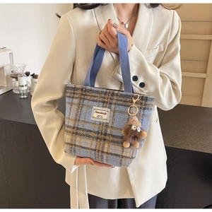 Détail du sac cabas à carreaux bleu et jaune avec breloque peluche et anses en toile