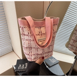 Detail of pink and white checkered tweed bucket bag with woven texture and logo patch