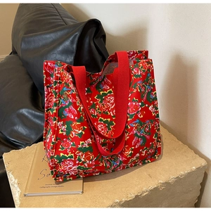 Close-up of a red tote bag with traditional Chinese floral pattern on a stone base