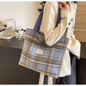 Détail du sac cabas à carreaux en laine avec étiquette en tissu sur fond de café