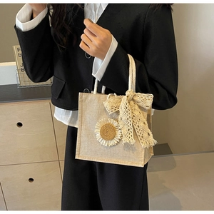 Detail of jute tote bag with floral applique, lace bow, and soft cotton rope handle