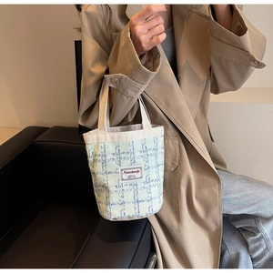Detail of light green checkered linen bucket bag with woven handles and brand label