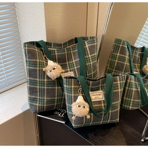 Detail of checkered canvas tote bag set with green straps and fuzzy eyeball pendant
