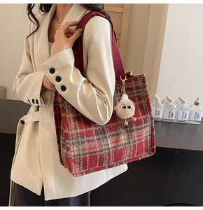 Detail of red plaid tweed tote bag with plush charm on a model in beige blazer