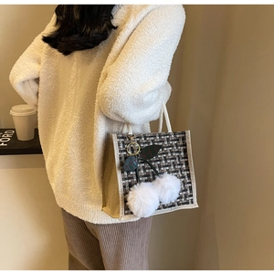 Detailed side view of linen woven lunch tote bag with cherry plush pendant charm