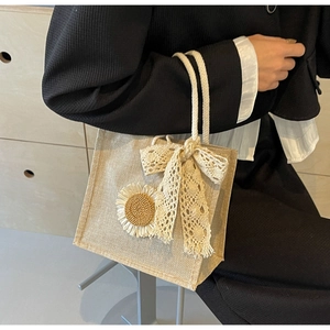Detailed view of linen tote bag featuring a white sunflower and delicate lace bow accent