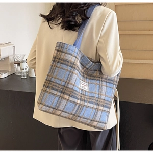 Sac fourre-tout en laine à carreaux bleu et marron porté à l'épaule sur le côté