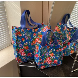 Detail of vintage floral canvas tote bags with vibrant peony print and sturdy blue handles